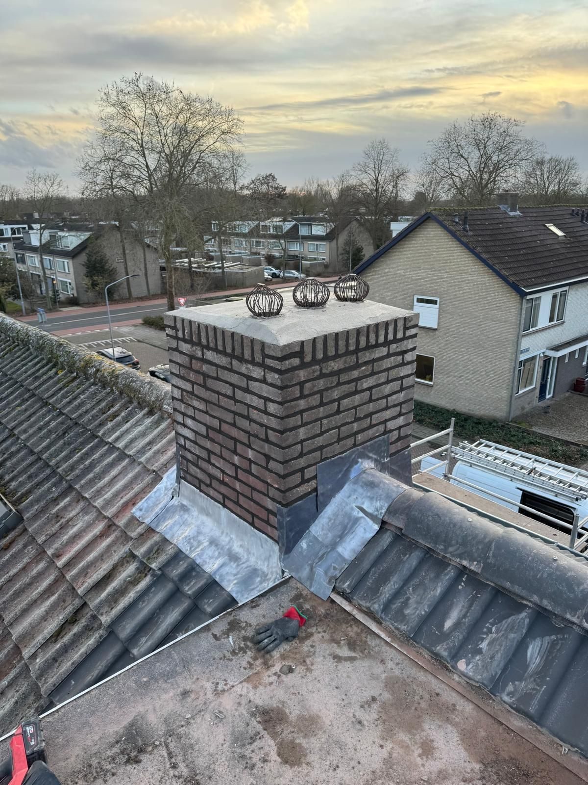Gerenoveerde schoorsteen met nieuw lood- en voegwerk op een dak