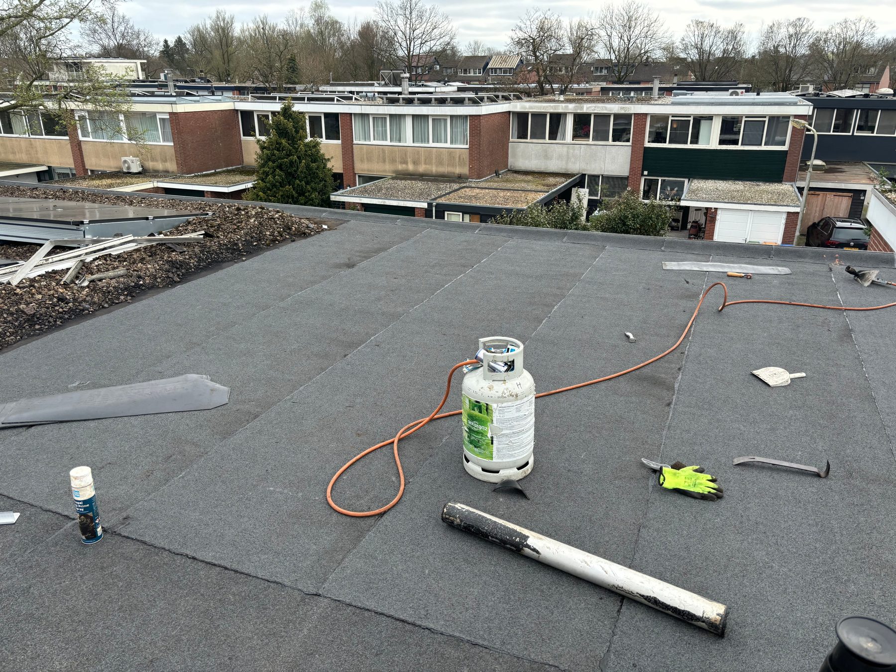 Dakdekkerswerkzaamheden in uitvoering met gasbrander op een plat dak